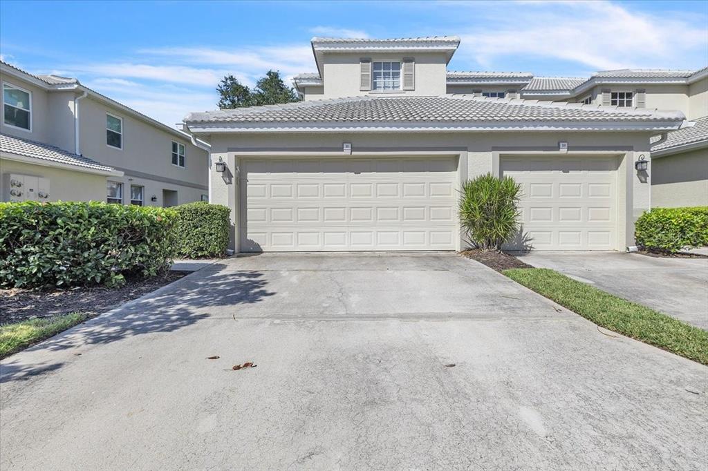 The exterior view shows a two-car garage with a concrete driveway and a tile roof — 3303 GRAND VISTA COURT UNIT 101, PORT CHARLOTTE, FL