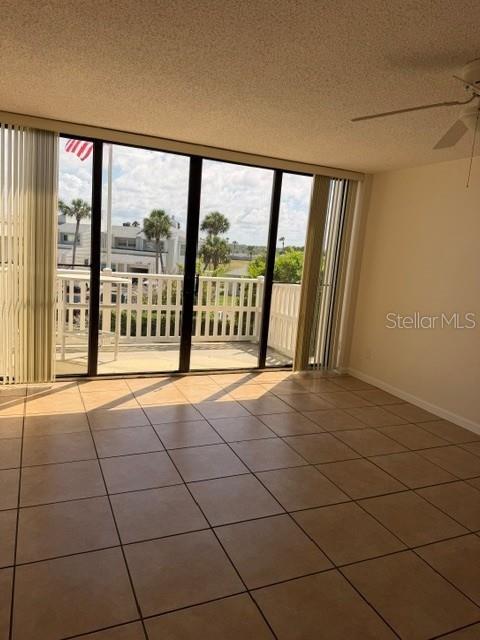 An empty room with tan tile flooring features a ceiling fan and large sliding glass doors — 3580 S OCEAN SHORE BOULEVARD UNIT 101, FLAGLER BEACH, FL