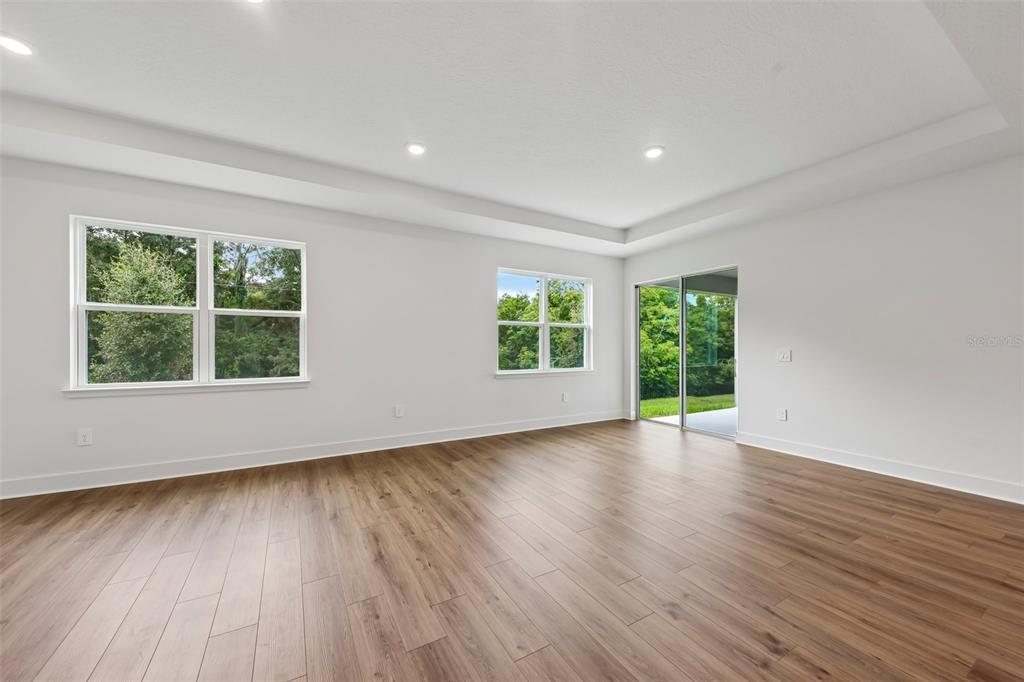An empty room with white walls, wood-look flooring, recessed lighting, and a sliding glass door — 786 EMERALD GROVE DRIVE, APOPKA, FL