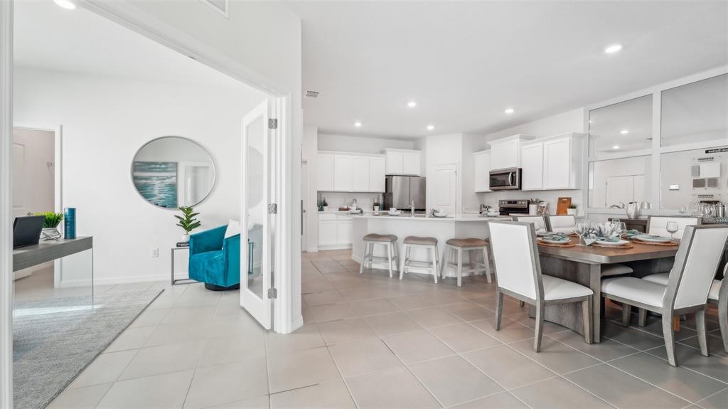 An open-concept kitchen and dining area with white cabinets, tile floors, and a home office — 33018 RUSTIC RISE ROAD, SAN ANTONIO, FL