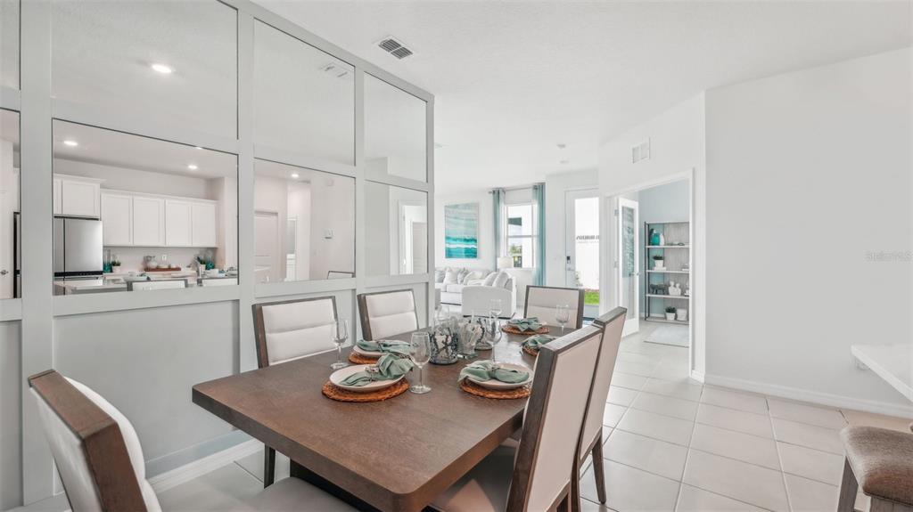 A dining area features a wooden table, upholstered chairs, and a mirrored wall partition — 33018 RUSTIC RISE ROAD, SAN ANTONIO, FL