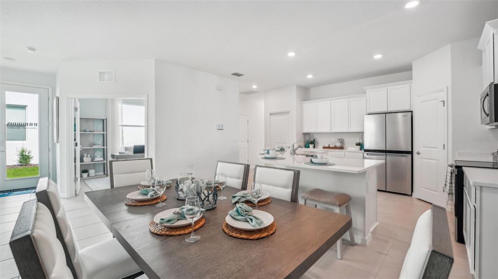 A dining area with a wooden table sits adjacent to a modern white kitchen — 33018 RUSTIC RISE ROAD, SAN ANTONIO, FL