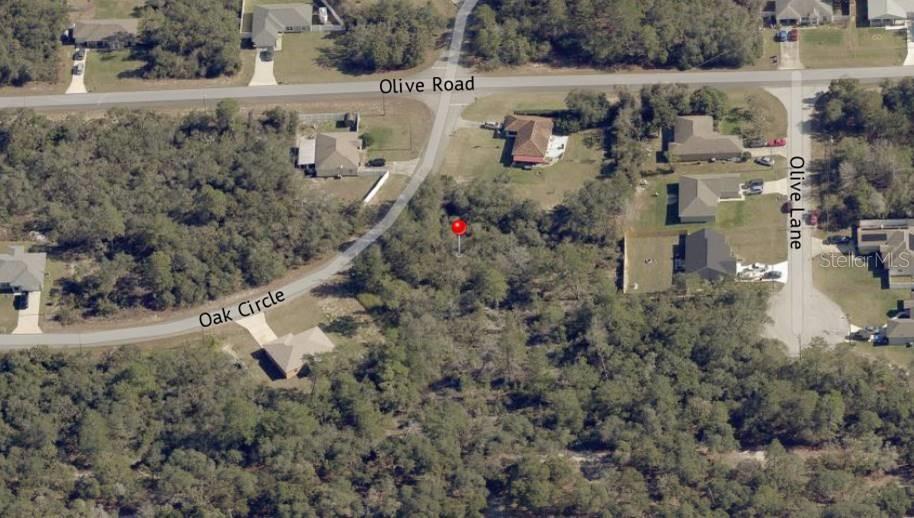 An aerial view shows a vacant wooded lot marked with a red pin near roads — Lot 9 OAK CIRCLE, OCALA, FL