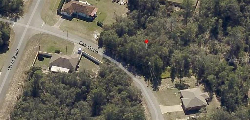 This aerial view shows a vacant wooded lot marked by a red pin on a road — Lot 9 OAK CIRCLE, OCALA, FL