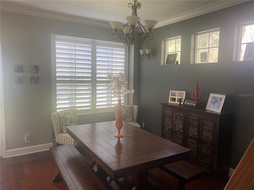 A dining room features a wooden table with benches, dark gray walls, and plantation shutters — 108 W LAKE VICTORIA CIRCLE, DELAND, FL