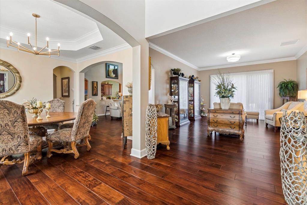 A dining area and living room feature dark wood floors and arched architectural transitions — 13800 CREST LAKE DRIVE, HUDSON, FL