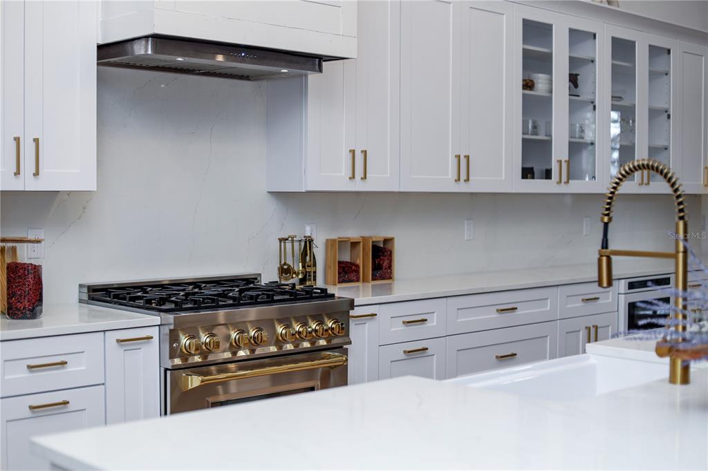 A modern kitchen features white cabinetry, gold hardware, a gas range, and white countertops — 3750 SE 139TH TERRACE, MORRISTON, FL