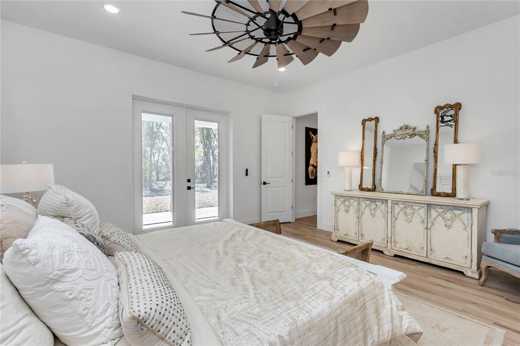 A bedroom features a windmill-style ceiling fan, a white dresser with mirrors, and glass doors — 3750 SE 139TH TERRACE, MORRISTON, FL