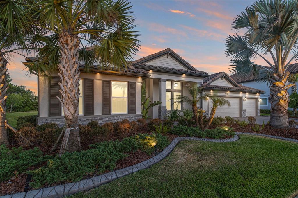 A modern living room features a white sectional sofa, marble fireplace wall, and large sliding doors — 7190 GRAYBROOK DRIVE, WESLEY CHAPEL, FL