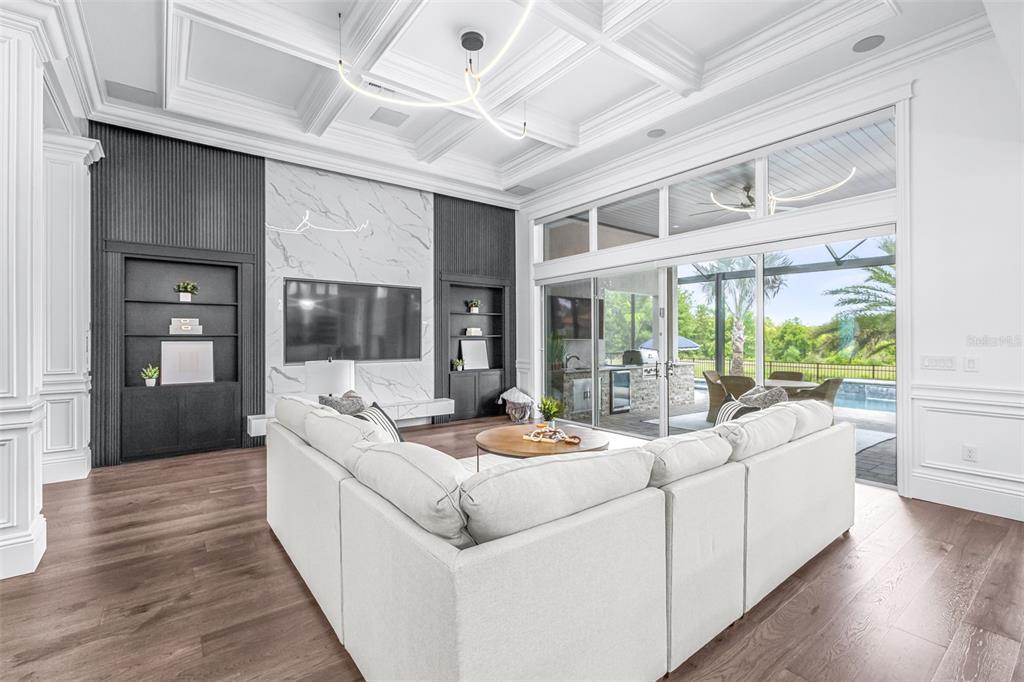 A modern living room features a fireplace, built-in shelving, a sofa, and a game table — 7190 GRAYBROOK DRIVE, WESLEY CHAPEL, FL