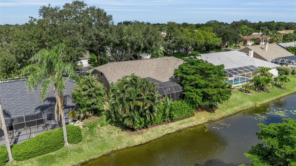 An aerial view of a suburban house with a screened pool enclosure beside a canal — 4739 SPRING MEADOW LANE, SARASOTA, FL