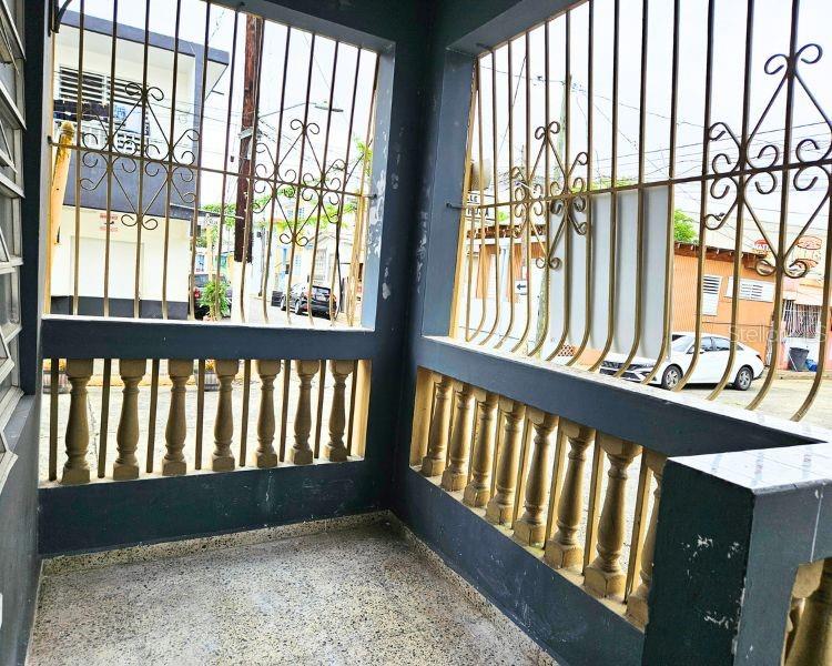 An outdoor porch features a terrazzo floor, decorative balustrades, and black metal security bars — 115 COMM PARIS 115, ESQUINA DE LA CRUZ ROJA CALLE DR., MAYAGUEZ, PR