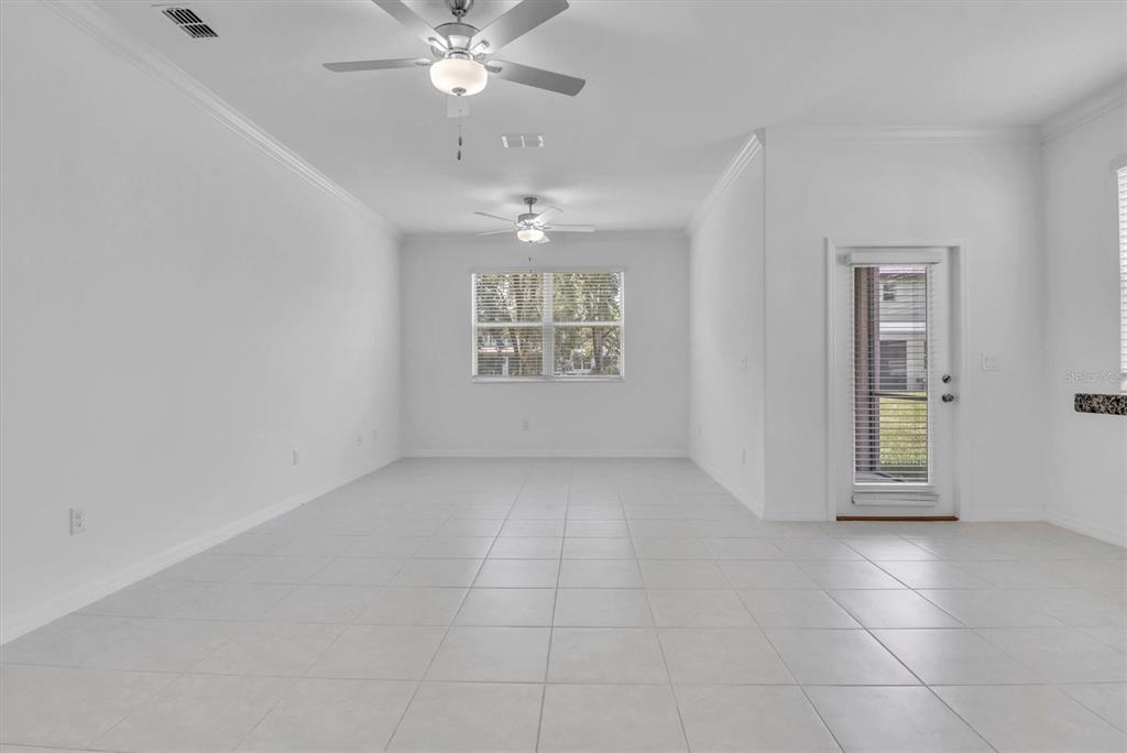 An empty room with white walls, tile flooring, two ceiling fans, and a glass door — 30687 VERIDIAN WAY, WESLEY CHAPEL, FL