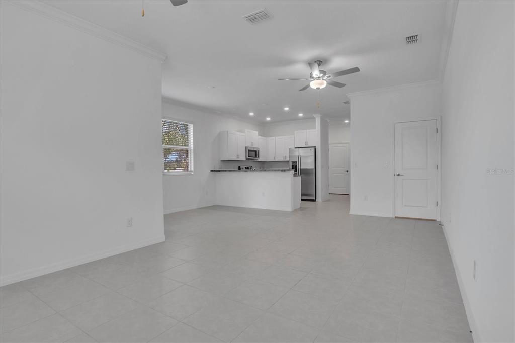 An open-concept kitchen with white cabinets and a breakfast bar overlooks a tiled living area — 30687 VERIDIAN WAY, WESLEY CHAPEL, FL