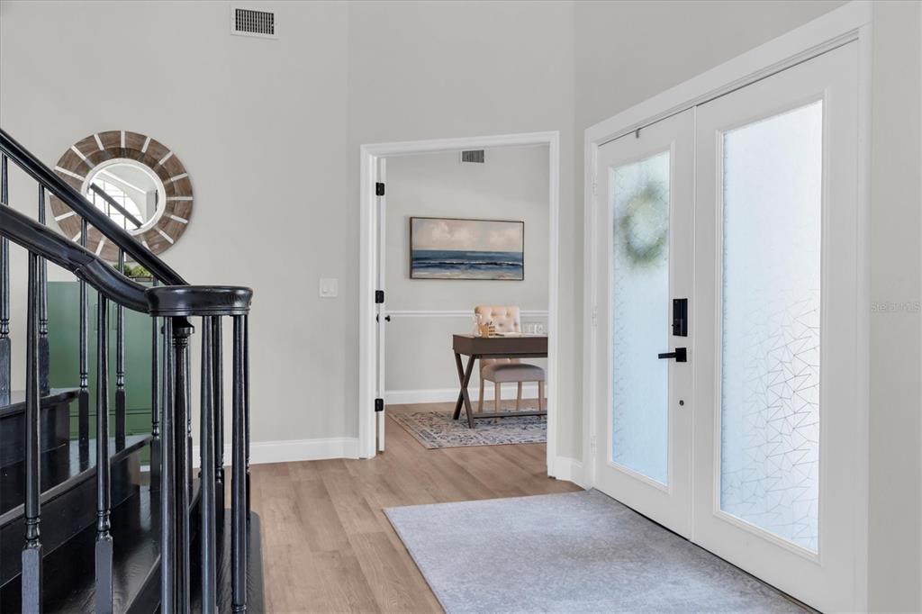 An entryway features a black staircase, a double front door, and a view into an office — 1625 PERCHERON DRIVE, TRINITY, FL