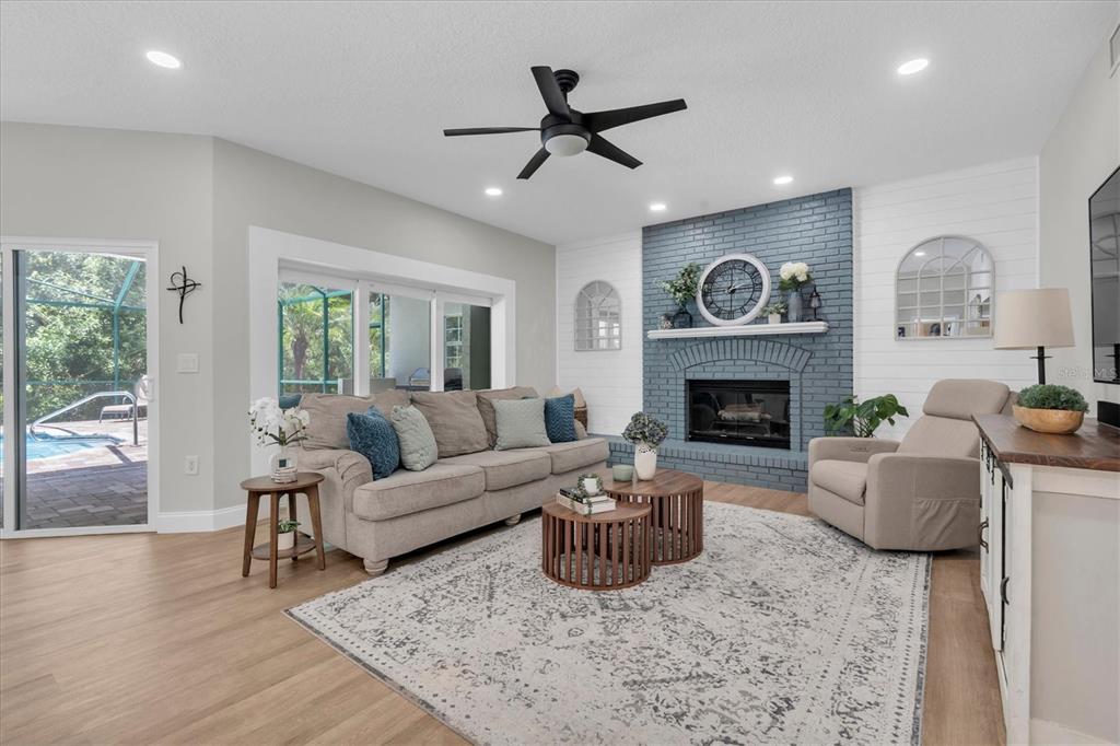 A living room features a blue brick fireplace, a beige sofa, and a sliding glass door — 1625 PERCHERON DRIVE, TRINITY, FL