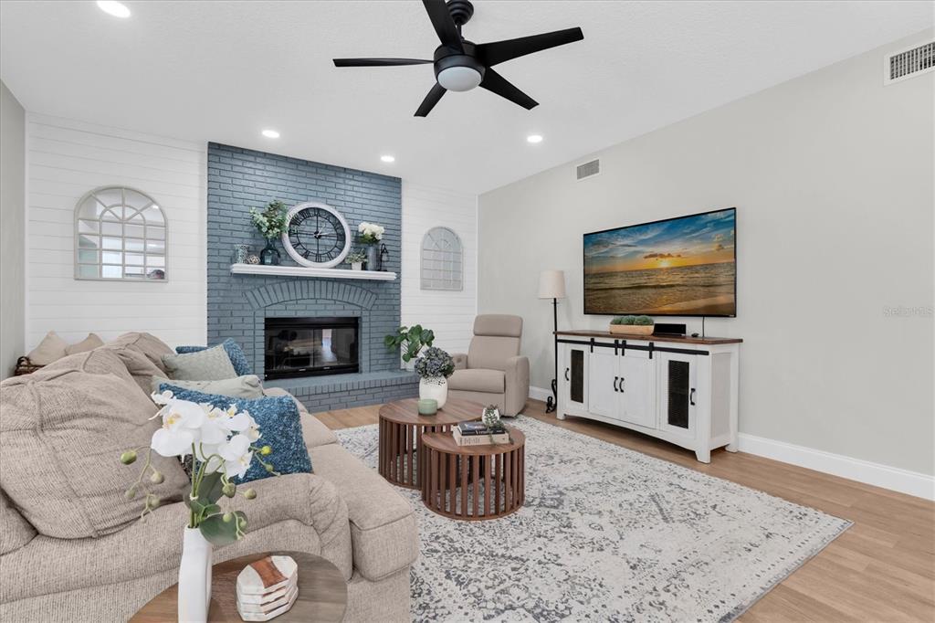 A living room features a blue brick fireplace, white shiplap walls, and a television console — 1625 PERCHERON DRIVE, TRINITY, FL