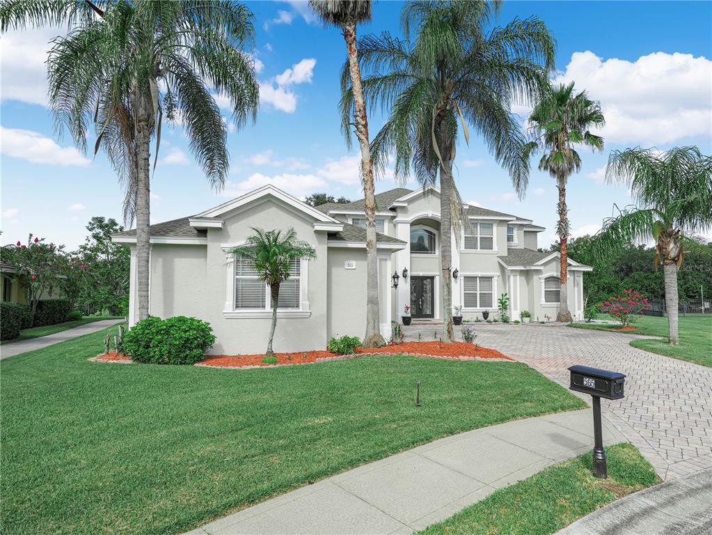 A two-story house with a paved driveway, palm trees, and a green lawn — 565 WHISPER WOODS DRIVE, LAKELAND, FL