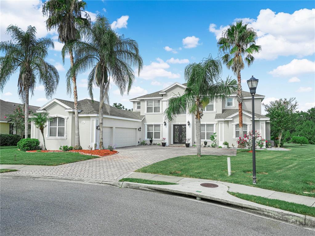 A two-story house with a paved driveway, a three-car garage, and palm trees in front — 565 WHISPER WOODS DRIVE, LAKELAND, FL