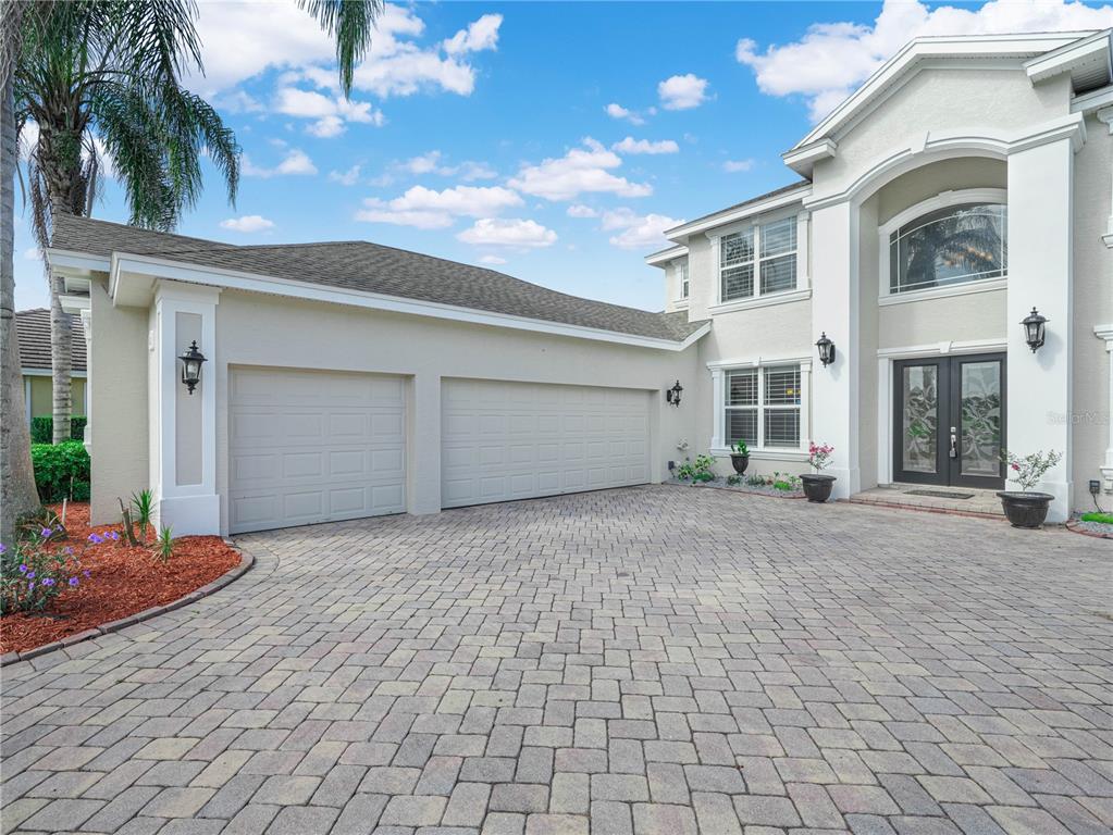 A two-story house with a three-car garage and a paved driveway under a blue sky — 565 WHISPER WOODS DRIVE, LAKELAND, FL