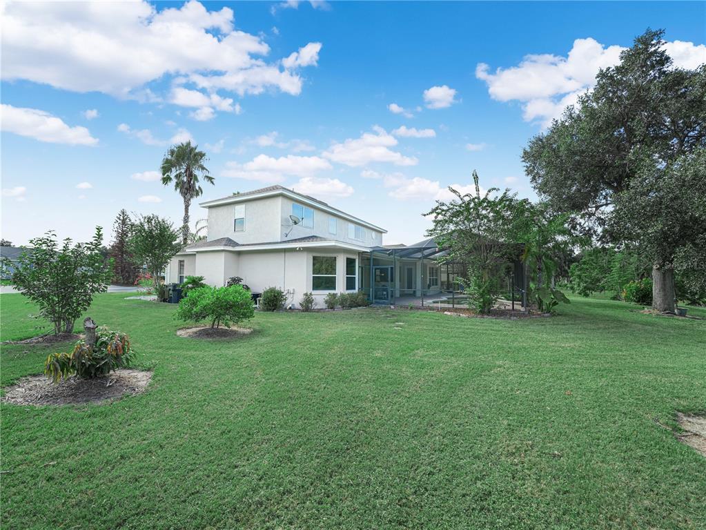The exterior of a two-story house features a screened-in pool area and a large lawn — 565 WHISPER WOODS DRIVE, LAKELAND, FL