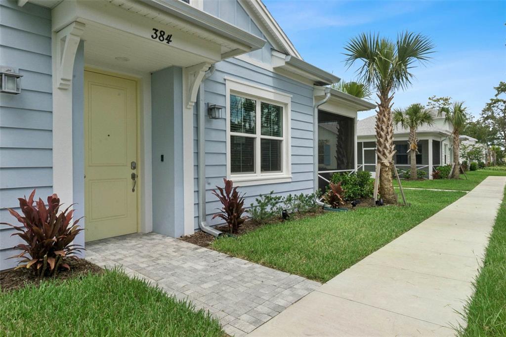 A light blue house with a yellow front door and a paved walkway — 384 GYPSY PALACE LANE, DAYTONA BEACH, FL