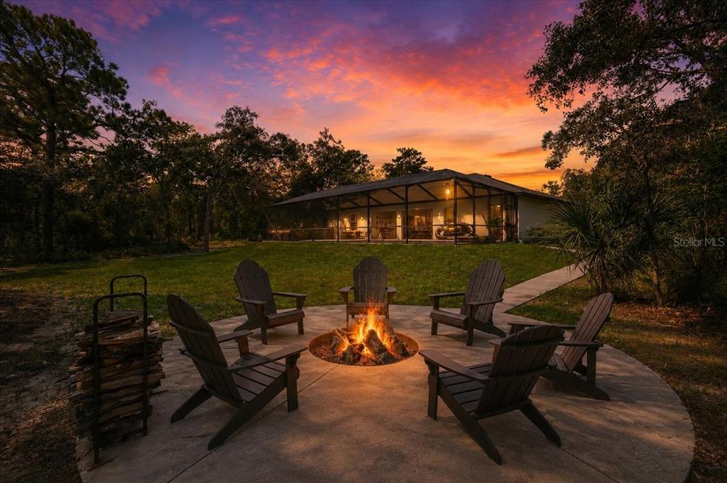 A fire pit with Adirondack chairs sits on a patio in front of a house — 15488 SCOLDER LOOP, WEEKI WACHEE, FL