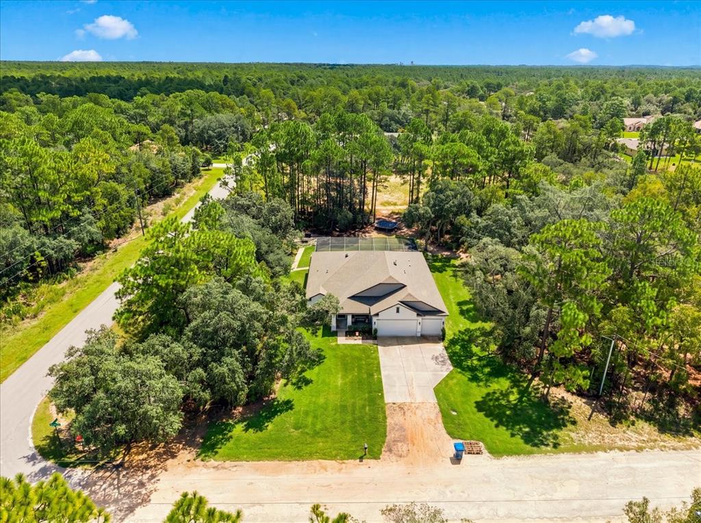 An aerial view of a single-story house with a pool cage surrounded by dense woods — 15488 SCOLDER LOOP, WEEKI WACHEE, FL