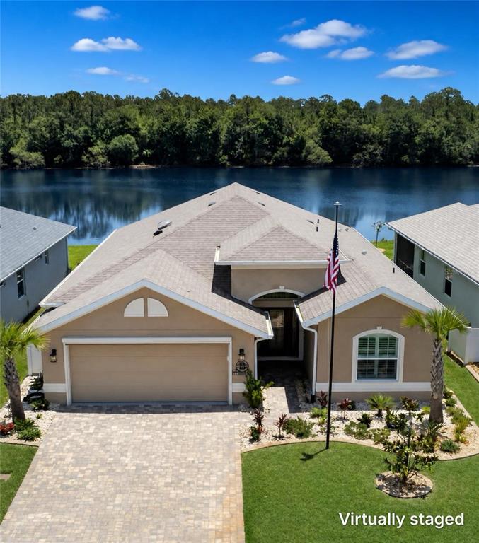 A tan single-story house with a paved driveway, a front lawn, and an American flag — 37 LAGOON WAY, PALM COAST, FL