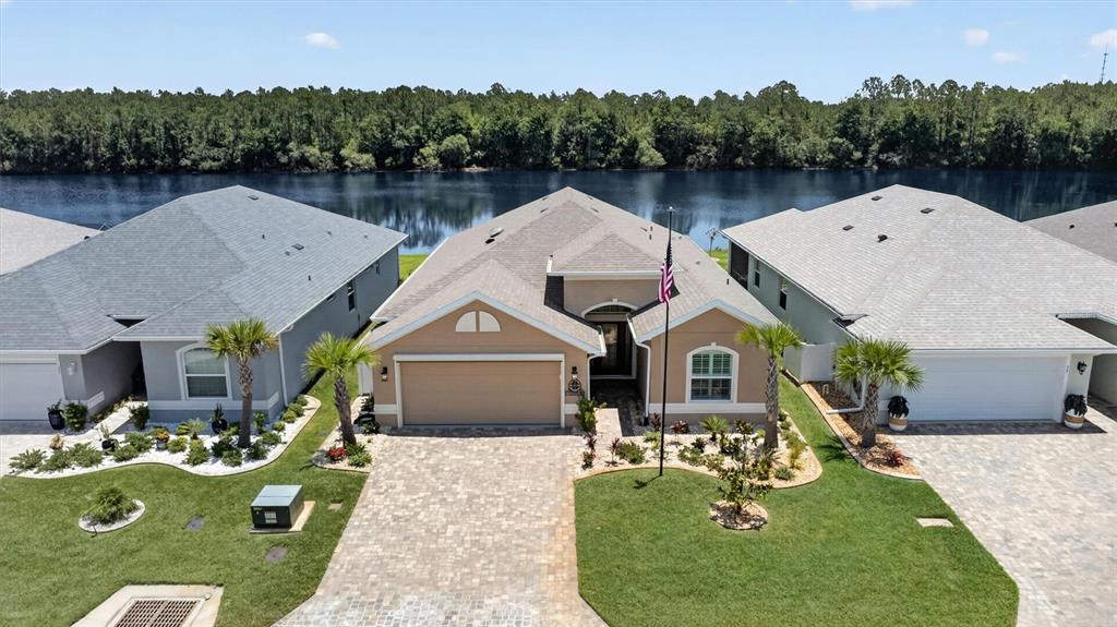 A single-story tan house with a paved driveway, a two-car garage, and a front lawn — 37 LAGOON WAY, PALM COAST, FL