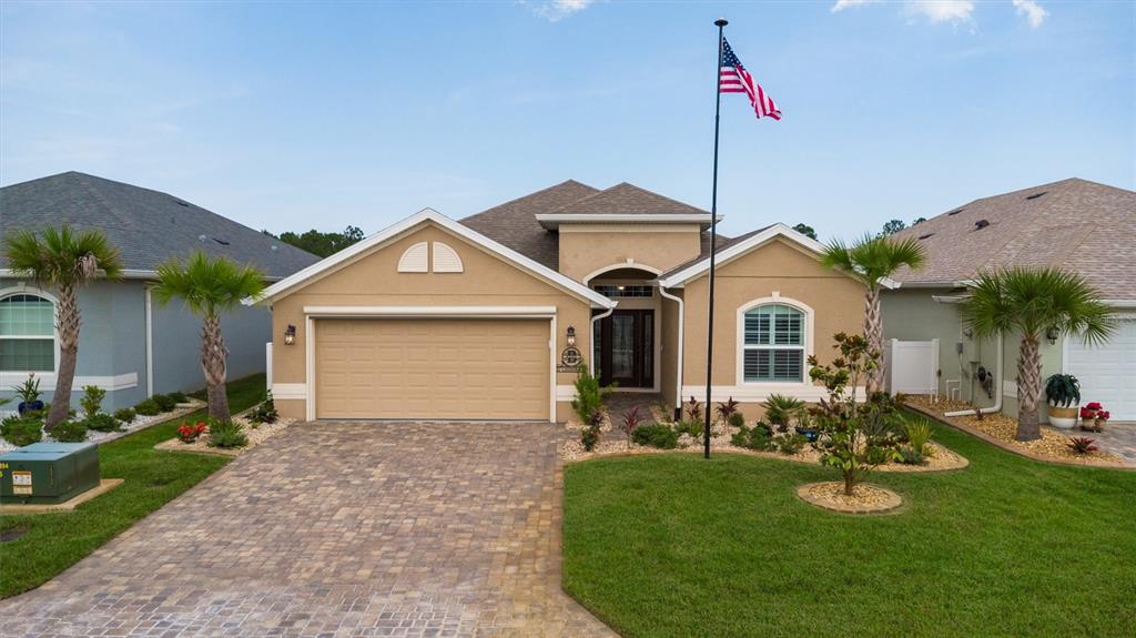 A tan single-story house with a paved driveway, palm trees, and a manicured lawn — 37 LAGOON WAY, PALM COAST, FL