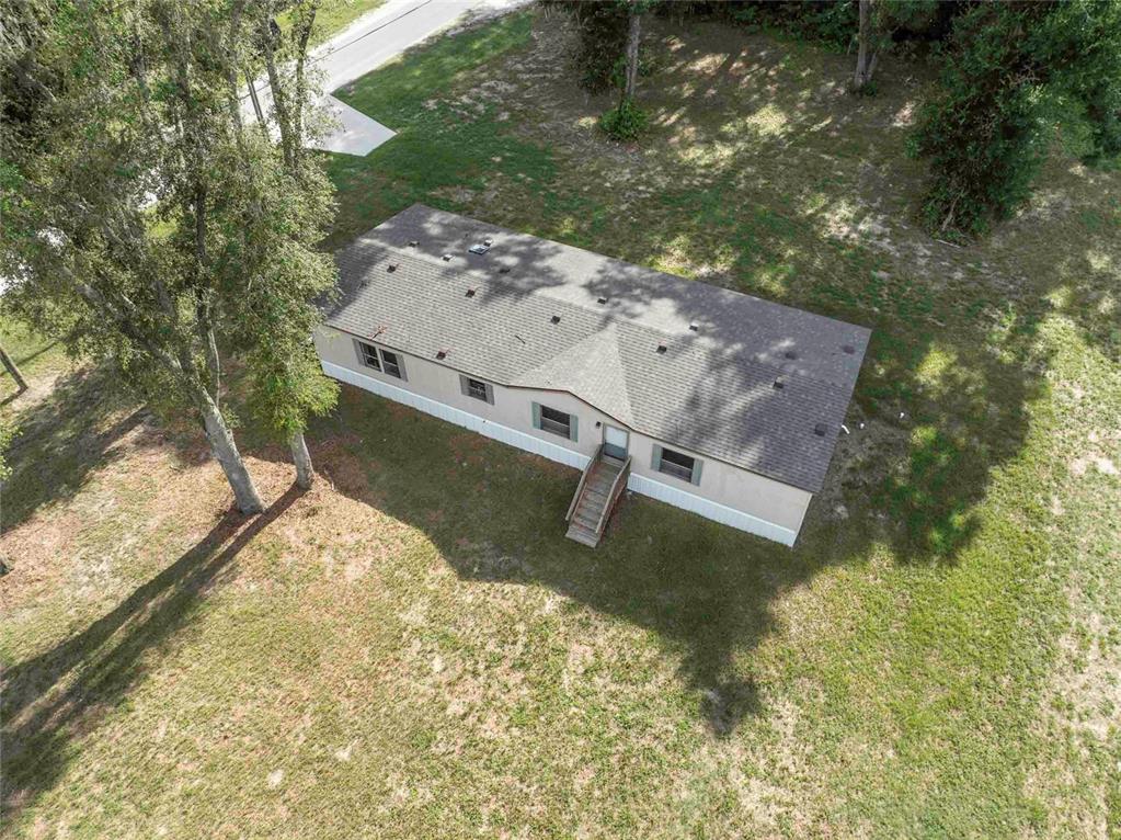 A single-story manufactured home with tan siding sits on a grassy lot near trees — 968 CR222 ROAD, OXFORD, FL