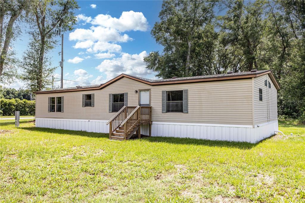 An aerial view shows a single-story manufactured home with a shingled roof and wooden steps — 968 CR222 ROAD, OXFORD, FL