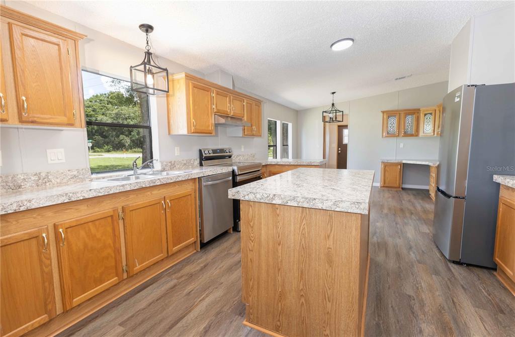 An open-concept living room with light gray walls, wood-look flooring, and a ceiling fan — 968 CR222 ROAD, OXFORD, FL