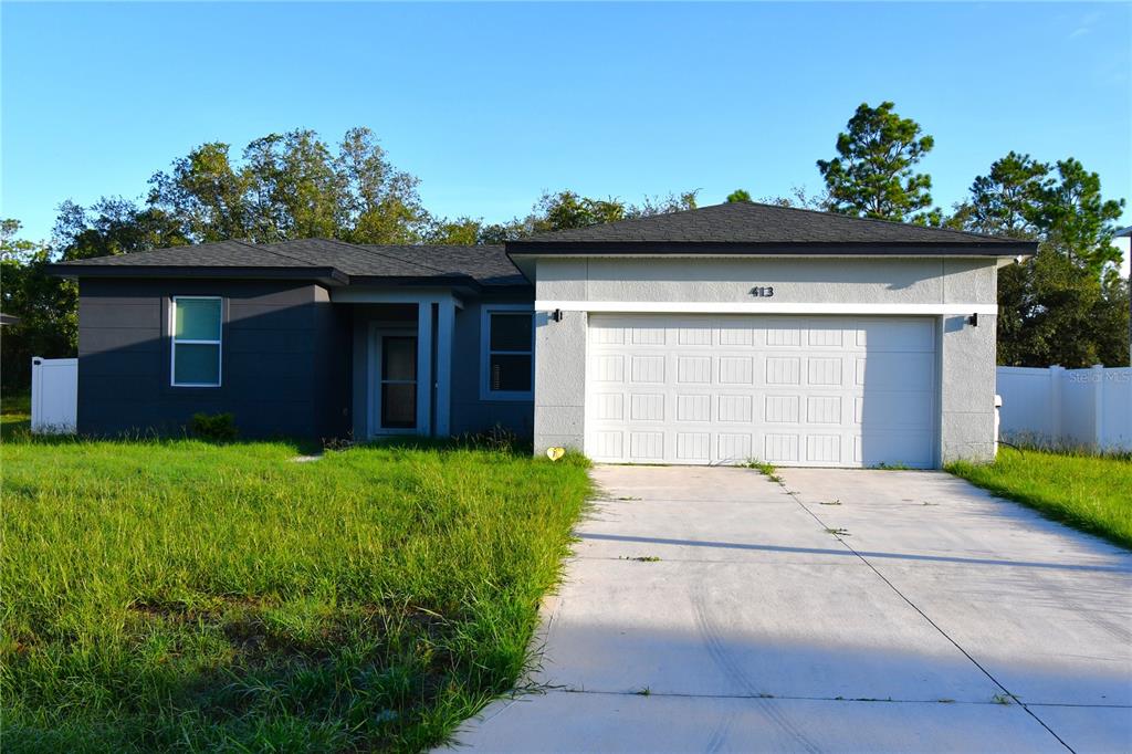 A single-story house with a two-car garage, gray exterior, and a concrete driveway — 413 ST JOHNS LANE, POINCIANA, FL