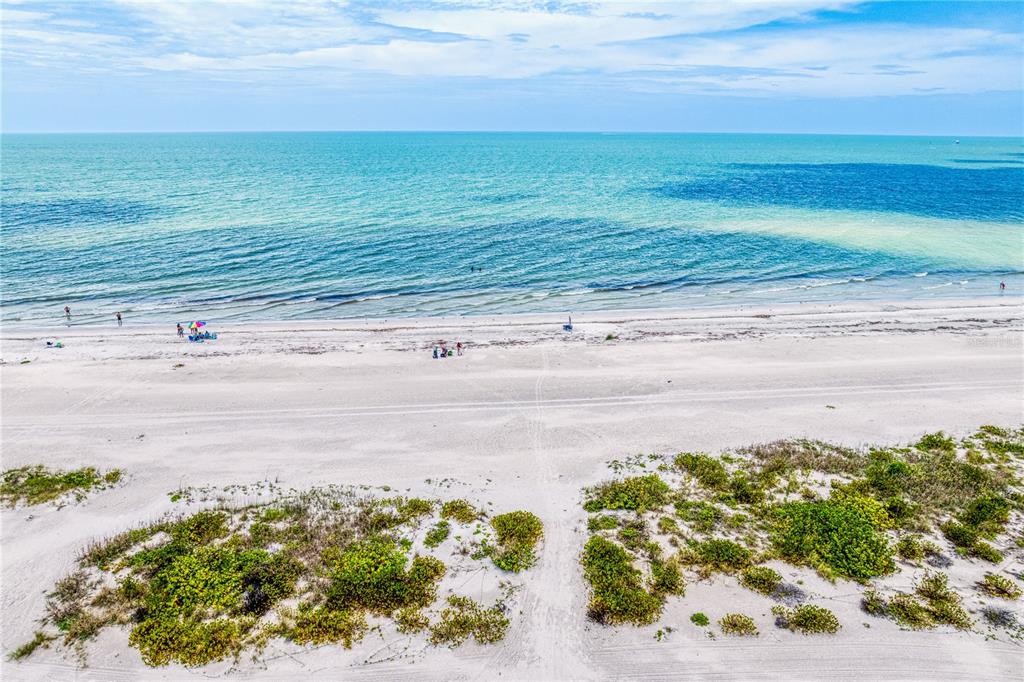 An aerial view shows a multi-story apartment building with a parking lot and beach access — 1250 GULF BOULEVARD UNIT 302, CLEARWATER BEACH, FL