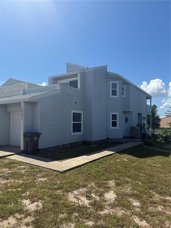 A light gray, multi-level residential building features horizontal siding, a garage, and a concrete walkway — 3501 S CENTRAL AVENUE, FLAGLER BEACH, FL