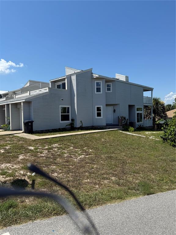 A two-story, light gray vinyl-sided townhouse features a covered entrance and a second-story balcony — 3501 S CENTRAL AVENUE, FLAGLER BEACH, FL