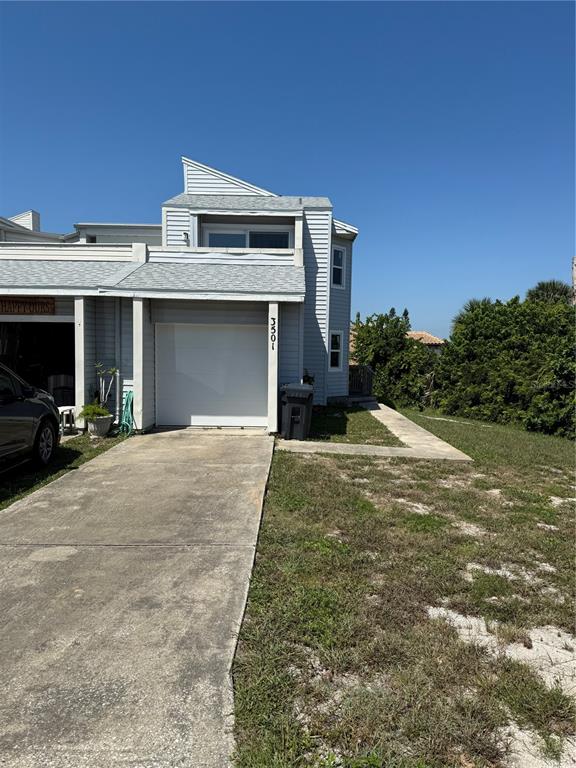 A two-story townhouse exterior features a white garage door, light siding, and a concrete driveway — 3501 S CENTRAL AVENUE, FLAGLER BEACH, FL