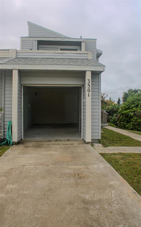 An exterior view of a residential building featuring an open garage and a concrete driveway — 3501 S CENTRAL AVENUE, FLAGLER BEACH, FL