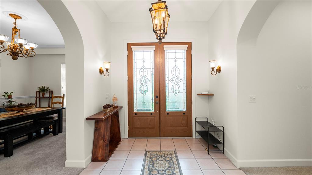 An entryway features a double front door, tile flooring, a hanging lantern, and a dining area — 318 HAMILTON SHORES DRIVE NE, WINTER HAVEN, FL