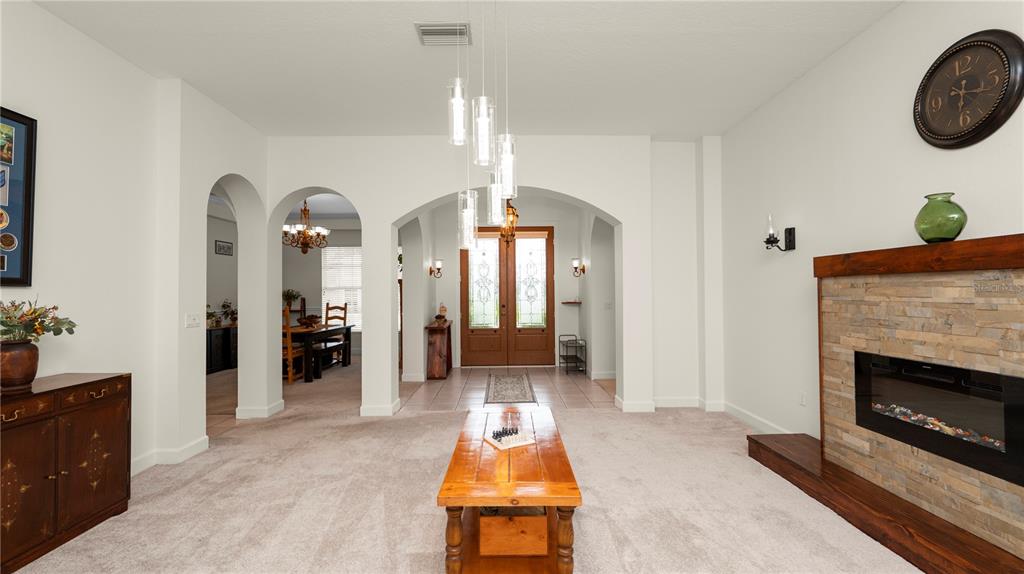 A living room features a stone fireplace, a wooden coffee table, and arched entryways — 318 HAMILTON SHORES DRIVE NE, WINTER HAVEN, FL