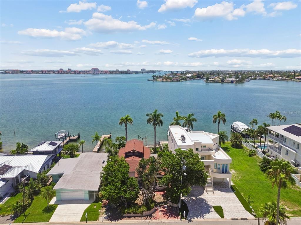 An aerial view shows waterfront homes with docks, palm trees, and a large bay — 720 BOCA CIEGA ISLE DRIVE, ST PETE BEACH, FL