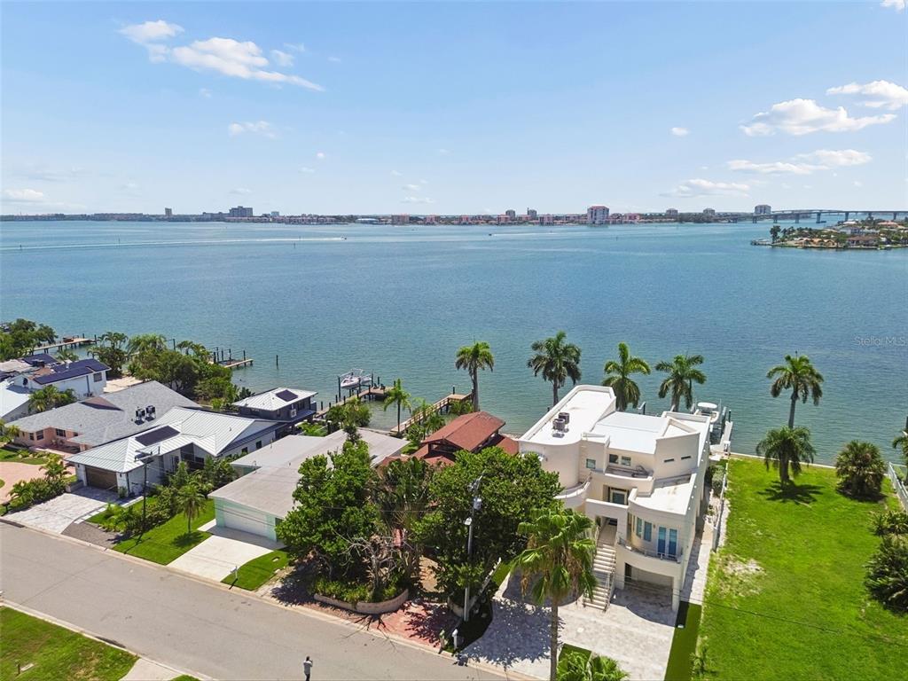 An aerial view shows waterfront homes with docks, palm trees, and a large bay — 720 BOCA CIEGA ISLE DRIVE, ST PETE BEACH, FL