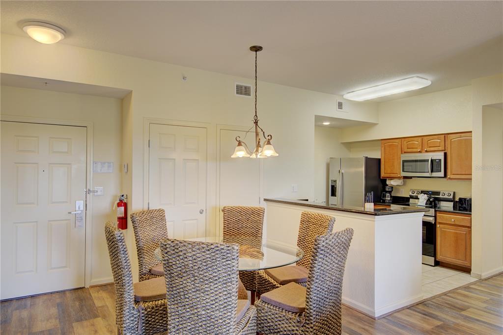 A dining area with a glass table and wicker chairs sits adjacent to a kitchen — 8101 RESORT VILLAGE DRIVE UNIT 31101, ORLANDO, FL