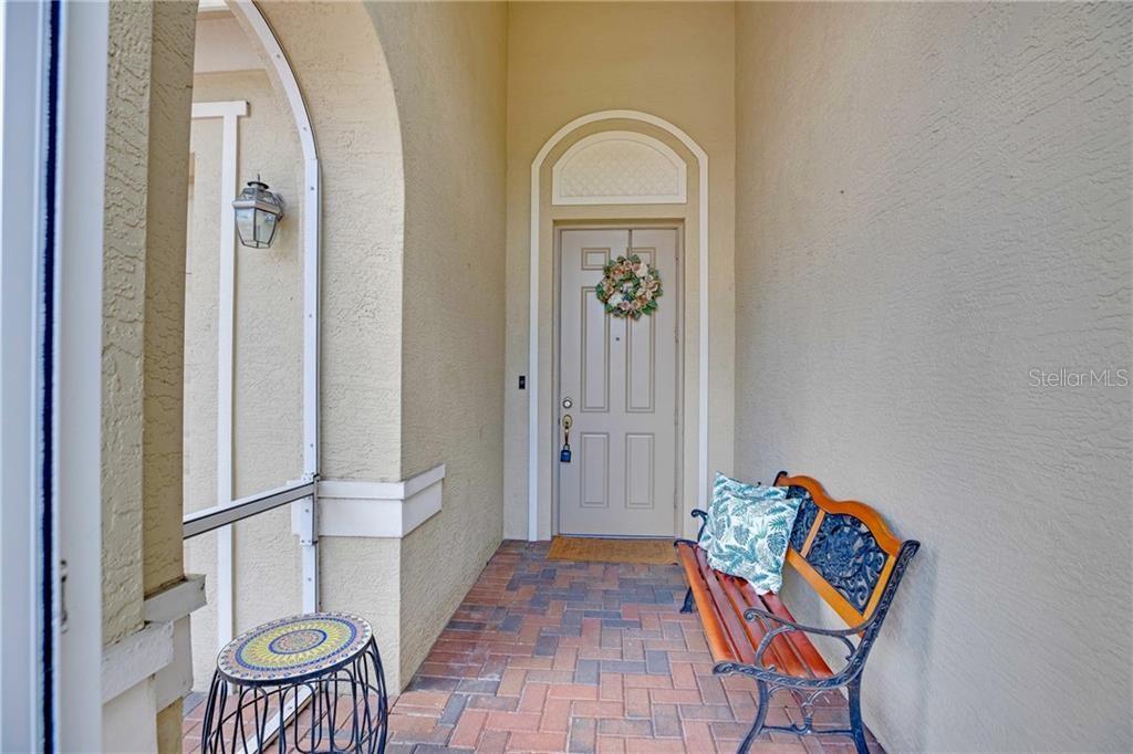 A covered entryway features a brick floor, a bench, and a front door with a wreath — 3189 ASTOR AVENUE, VERO BEACH, FL