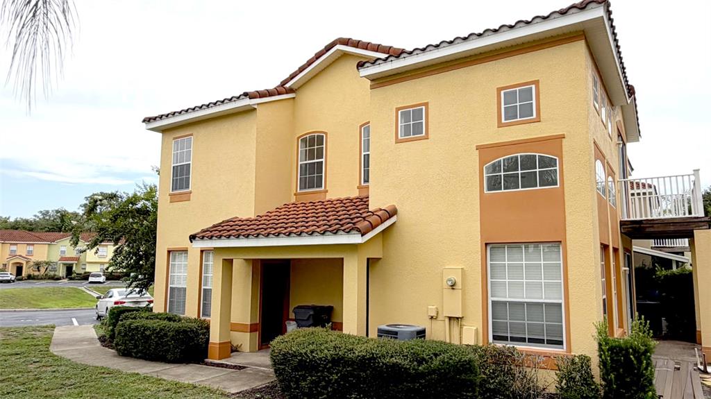 A two-story yellow stucco house with a tiled roof and a small balcony — 203 MADISON CIRCLE, DAVENPORT, FL