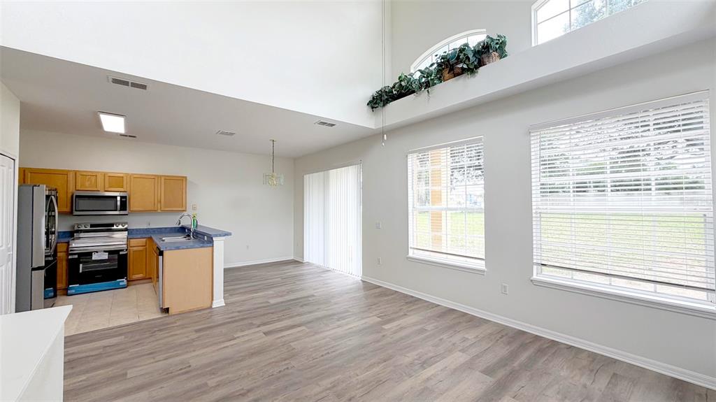 A kitchen with light wood cabinets and a dining area with high ceilings and windows — 203 MADISON CIRCLE, DAVENPORT, FL