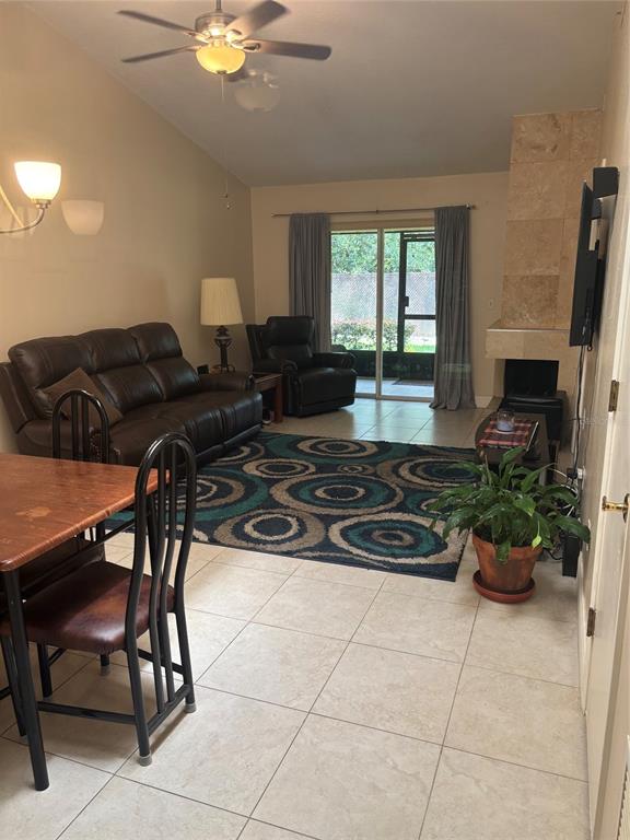 A living room features tile floors, a brown leather sofa, a recliner, and a fireplace — 283 HILL STREET UNIT 283, CASSELBERRY, FL