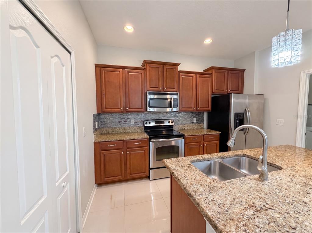 A kitchen features wood cabinets, granite countertops, stainless steel appliances, and a center island — 1308 SEBURN ROAD, APOPKA, FL